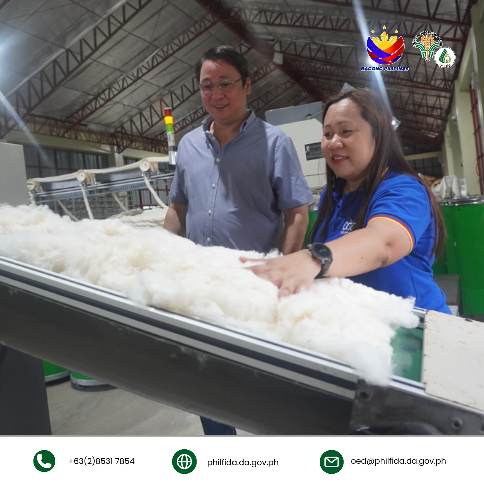 A man and woman inspecting cotton input to a processing machine in a processing center.