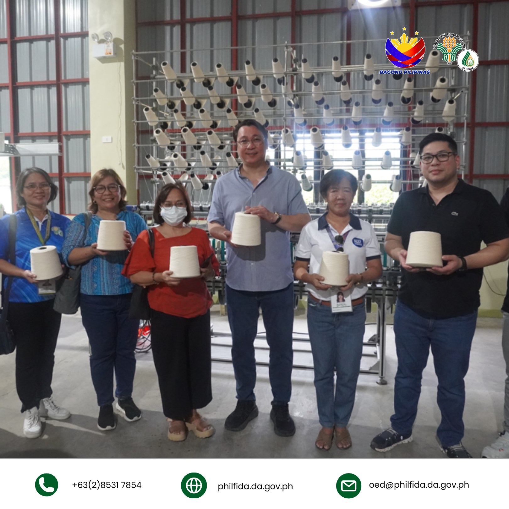 A group of people holding cotton yarn together in a processing center.