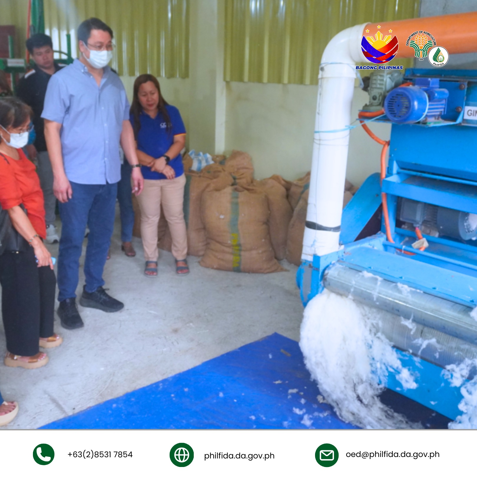 A man and woman inspect a cotton processing machine.